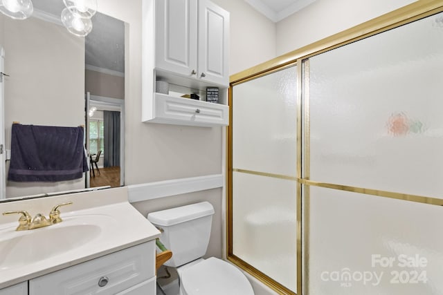 bathroom with vanity, toilet, a shower with door, and ornamental molding