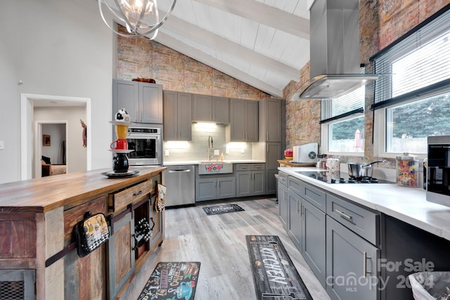 kitchen with high vaulted ceiling, gray cabinets, appliances with stainless steel finishes, light hardwood / wood-style floors, and island exhaust hood