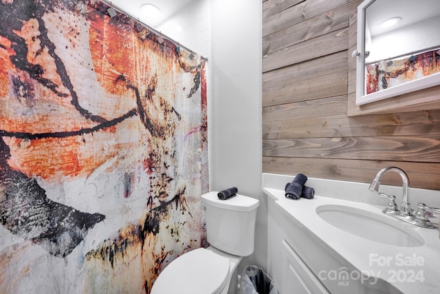 bathroom featuring vanity, toilet, walk in shower, and wood walls