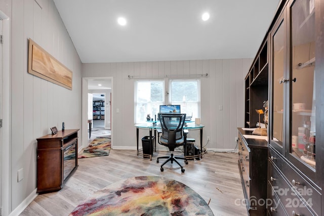 home office with light wood-type flooring, wooden walls, and vaulted ceiling