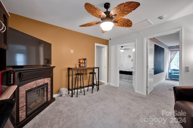 living area with ceiling fan, light colored carpet, and a fireplace