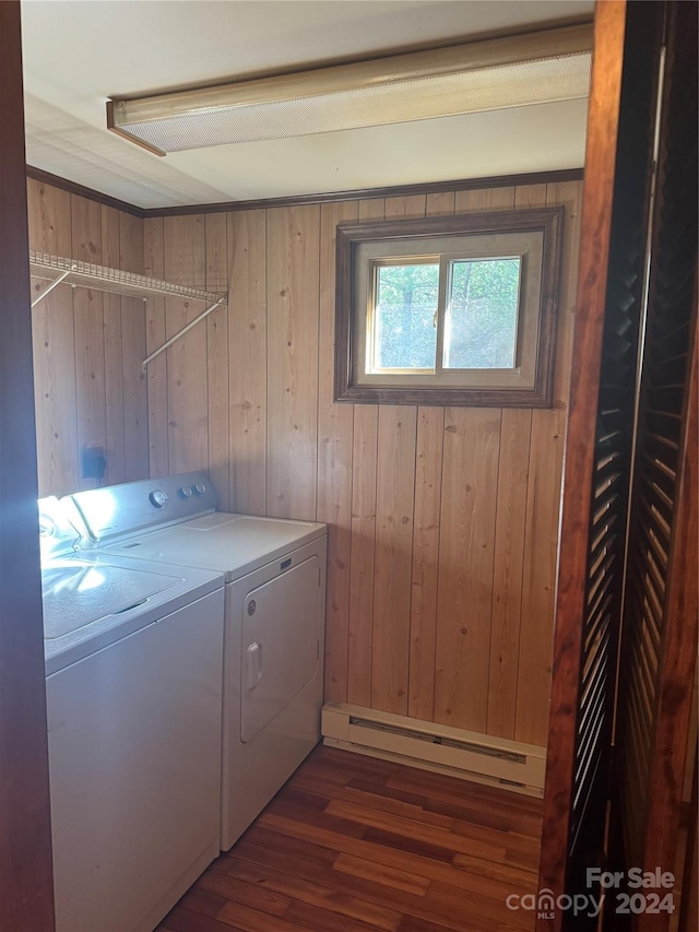 clothes washing area with wooden walls, dark wood-type flooring, a baseboard radiator, and independent washer and dryer