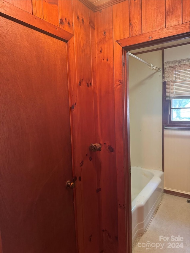 bathroom featuring wooden walls and a tub