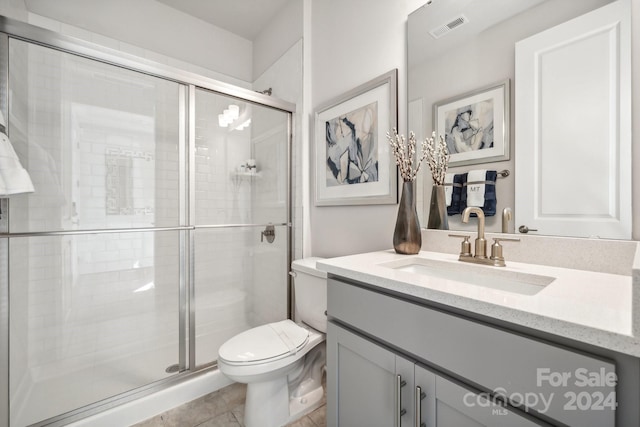 bathroom featuring tile patterned flooring, vanity, toilet, and walk in shower