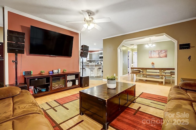 living room featuring crown molding, wood-type flooring, and ceiling fan with notable chandelier