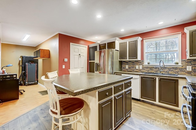 kitchen featuring sink, light hardwood / wood-style flooring, a breakfast bar area, stainless steel appliances, and a center island