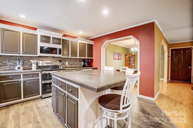 kitchen featuring range with two ovens, a breakfast bar area, light hardwood / wood-style floors, and a kitchen island