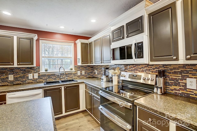 kitchen featuring sink, decorative backsplash, white appliances, light hardwood / wood-style floors, and a textured ceiling