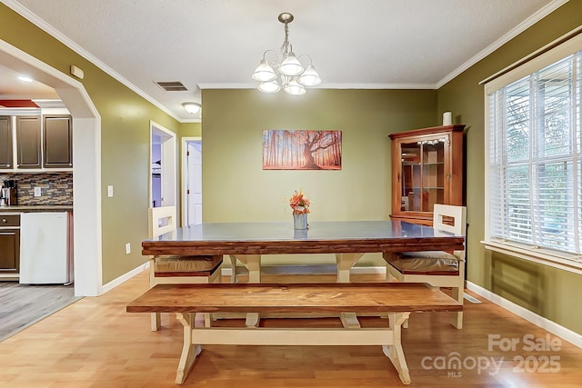 dining area with breakfast area, ornamental molding, a chandelier, and light hardwood / wood-style flooring