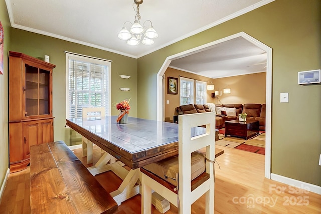 dining room featuring ornamental molding, a wealth of natural light, a chandelier, and light wood-type flooring