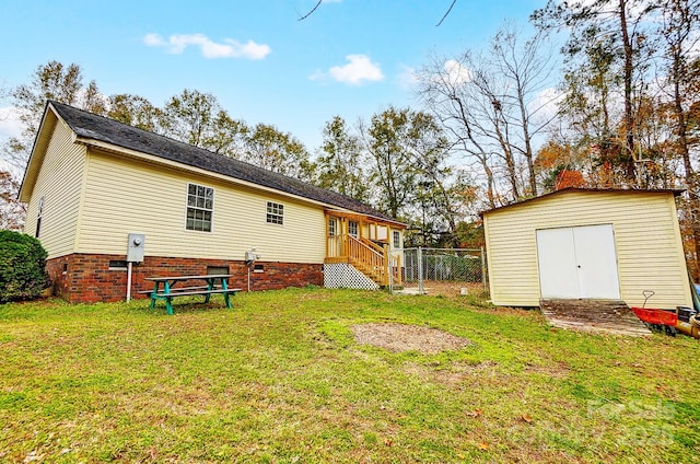 rear view of house featuring a lawn and a storage unit