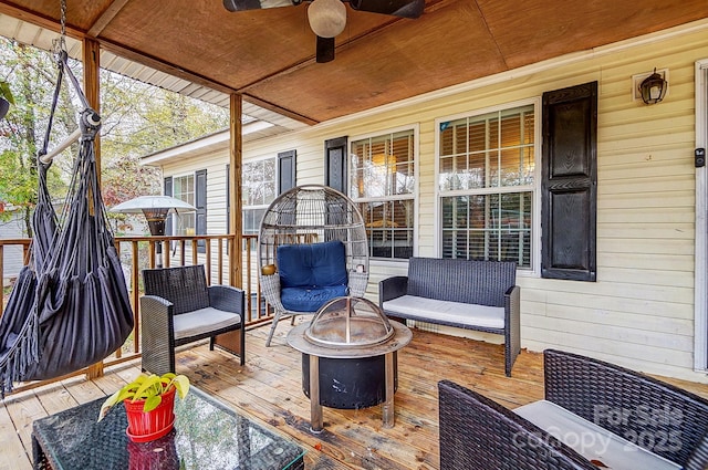 wooden deck with ceiling fan and an outdoor living space with a fire pit