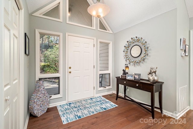 entrance foyer with a textured ceiling, dark wood-type flooring, and lofted ceiling