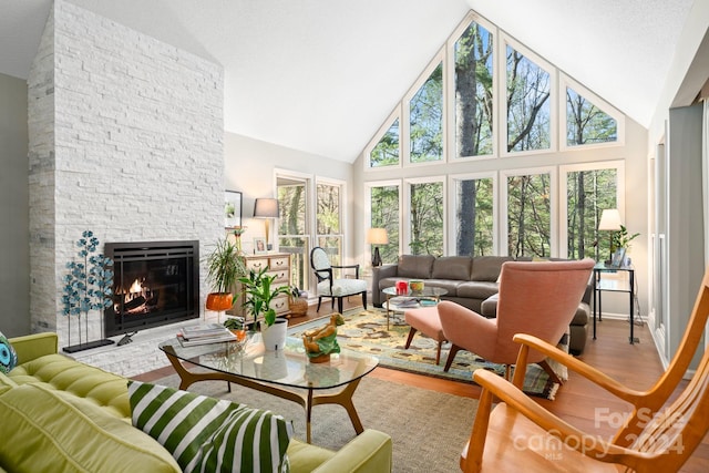 living room featuring a fireplace, high vaulted ceiling, hardwood / wood-style floors, and a textured ceiling