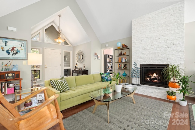 living room featuring hardwood / wood-style floors, a stone fireplace, and high vaulted ceiling