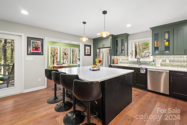 kitchen featuring plenty of natural light, a kitchen island, stainless steel appliances, and hanging light fixtures