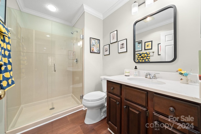 bathroom with ornamental molding, vanity, a shower with door, hardwood / wood-style floors, and toilet