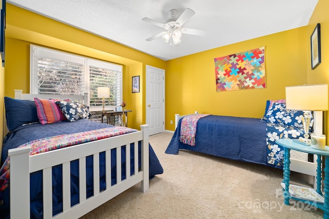 carpeted bedroom with ceiling fan and a textured ceiling