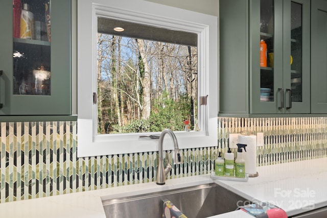 exterior details with light stone counters, sink, green cabinets, and french doors