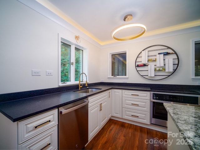 kitchen featuring appliances with stainless steel finishes, dark wood-type flooring, a sink, and white cabinetry