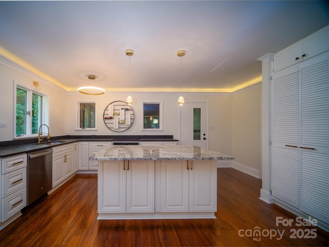 kitchen with pendant lighting, white cabinets, a sink, dark stone counters, and dishwasher