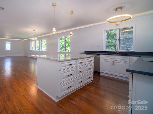 kitchen featuring decorative light fixtures, stainless steel dishwasher, open floor plan, white cabinets, and a sink