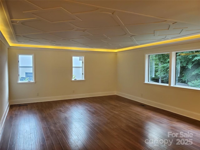 unfurnished room featuring dark wood-style flooring, visible vents, and baseboards