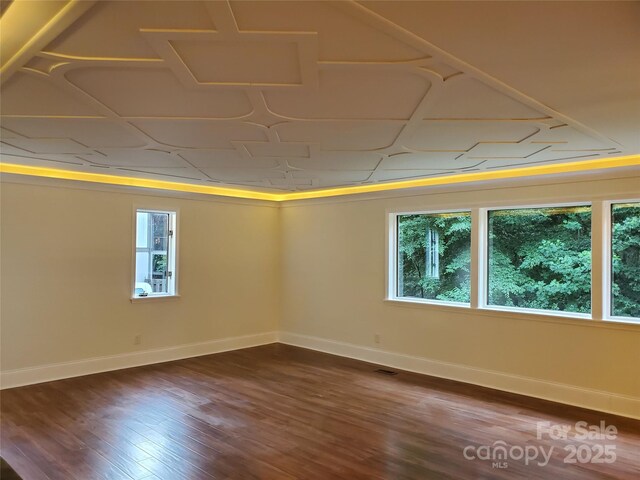 spare room with dark wood-style floors, visible vents, and baseboards