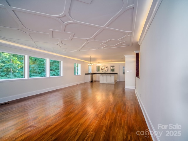 unfurnished living room featuring wood finished floors, visible vents, and baseboards