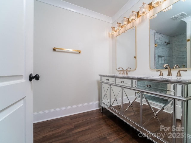 full bathroom featuring wood finished floors, a sink, visible vents, baseboards, and double vanity