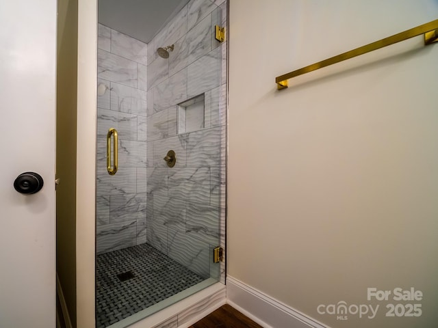 full bathroom with a stall shower and baseboards