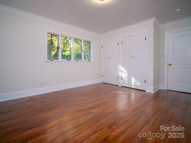 interior space with ornamental molding, dark wood-style flooring, and baseboards