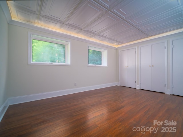 spare room with an ornate ceiling, baseboards, and dark wood finished floors