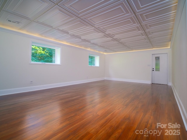 spare room featuring dark wood-style floors, an ornate ceiling, visible vents, and baseboards