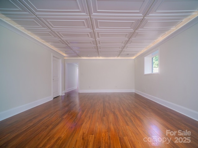 empty room featuring an ornate ceiling, baseboards, and dark wood-style flooring