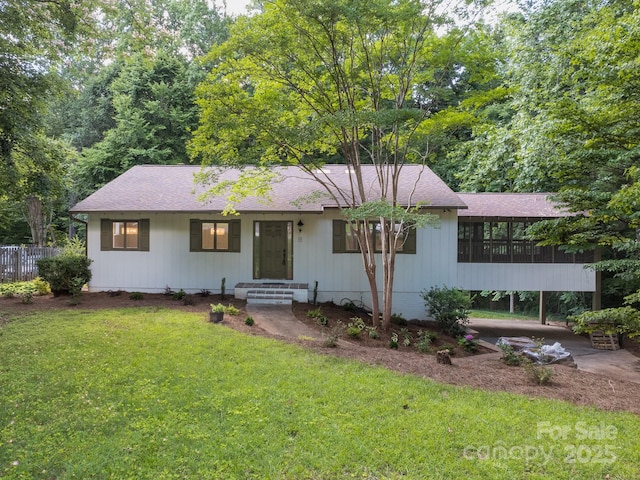 ranch-style home featuring roof with shingles and a front lawn