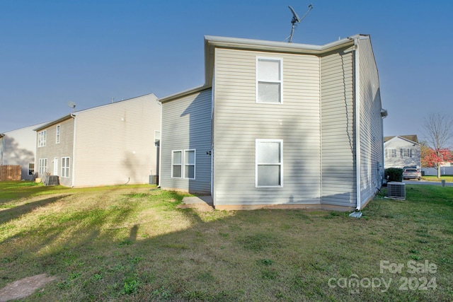 back of house with central AC unit and a yard