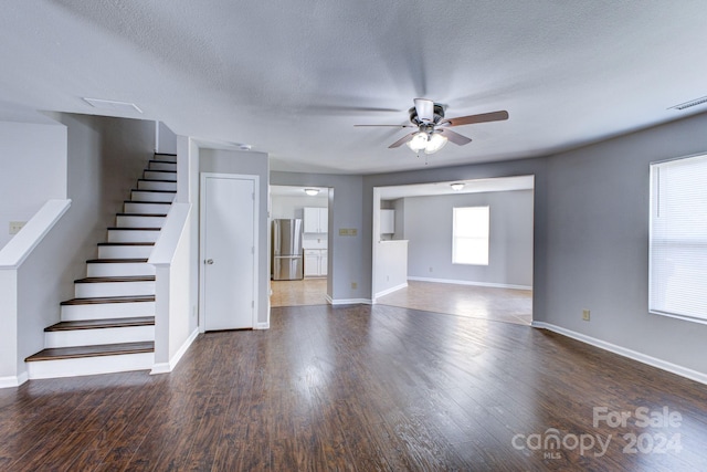 unfurnished living room with a textured ceiling, ceiling fan, and dark hardwood / wood-style floors