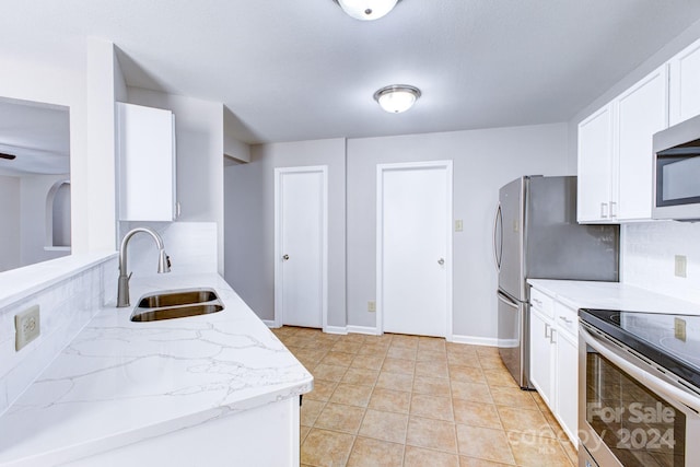 kitchen featuring decorative backsplash, stainless steel appliances, sink, light tile patterned floors, and white cabinets