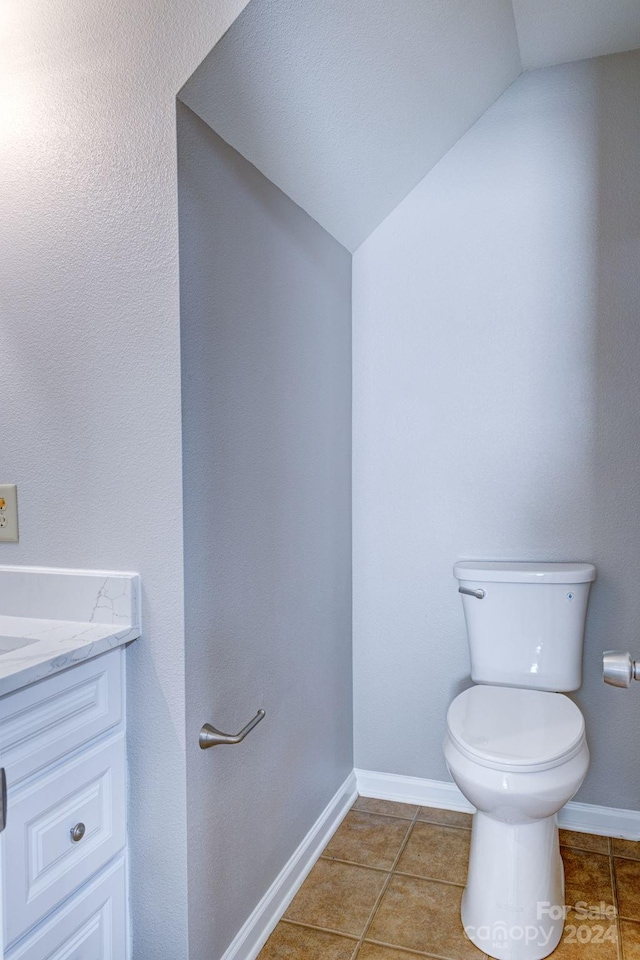 bathroom featuring toilet, vanity, tile patterned floors, and lofted ceiling