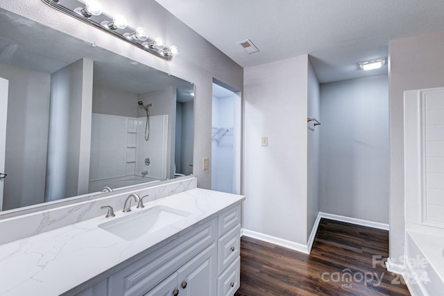 bathroom with shower / bathing tub combination, hardwood / wood-style floors, vanity, and a textured ceiling