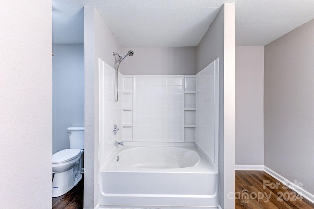 bathroom with a textured ceiling, hardwood / wood-style floors, bathtub / shower combination, and toilet