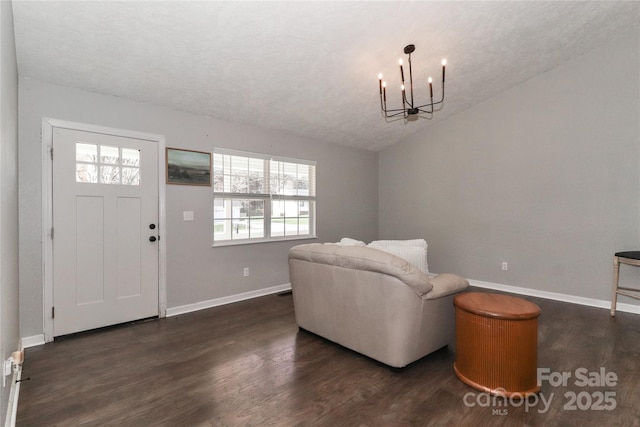 interior space with an inviting chandelier, vaulted ceiling, and dark hardwood / wood-style floors