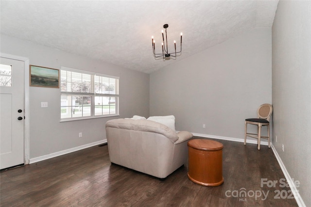 sitting room with lofted ceiling, dark wood-type flooring, a textured ceiling, and an inviting chandelier