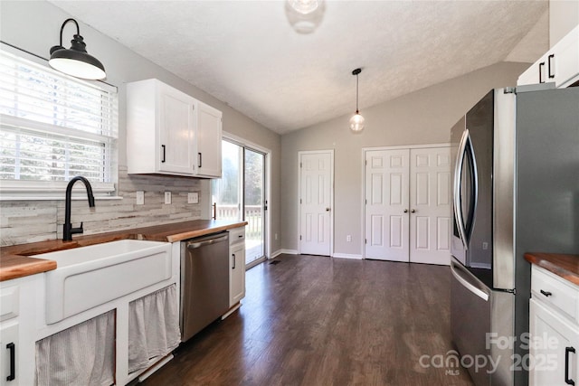 kitchen with pendant lighting, white cabinetry, appliances with stainless steel finishes, and butcher block counters