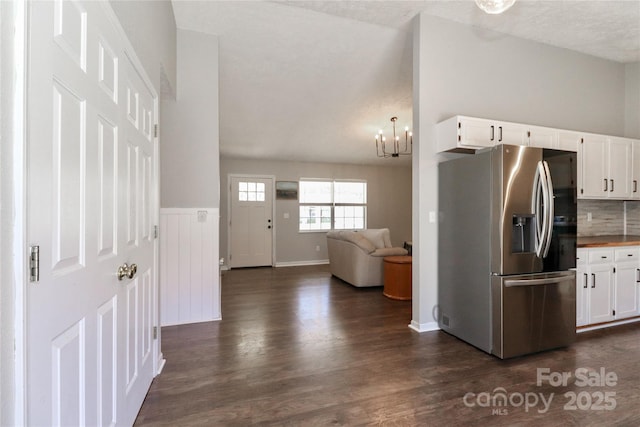 kitchen with white cabinetry, stainless steel fridge, dark hardwood / wood-style flooring, a notable chandelier, and decorative backsplash