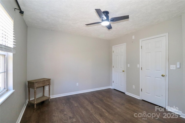 empty room featuring ceiling fan, dark hardwood / wood-style floors, and a textured ceiling