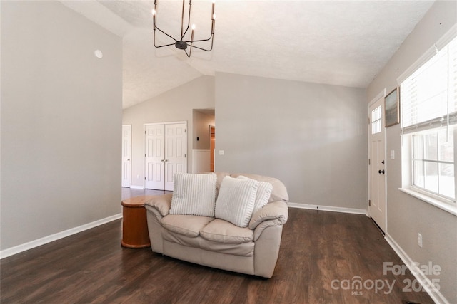 interior space featuring a notable chandelier, vaulted ceiling, baseboards, and wood finished floors