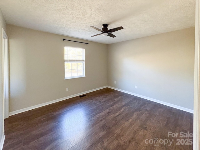 unfurnished room featuring dark wood-type flooring, visible vents, baseboards, and a ceiling fan