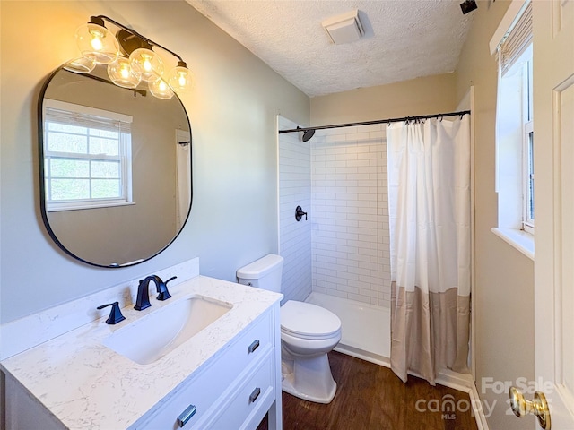 bathroom featuring a textured ceiling, toilet, wood finished floors, visible vents, and tiled shower